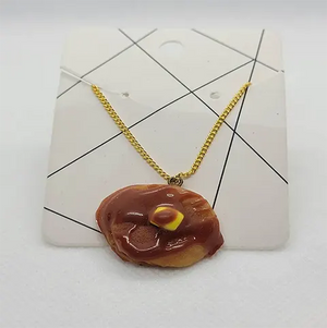 A two pancake stacked charm with syrup and butter attached to a gold chain