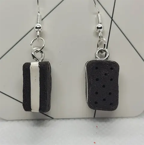 A pair of black rectangular ice cream sandwich earrings. One earring is sideways showing a strip of white